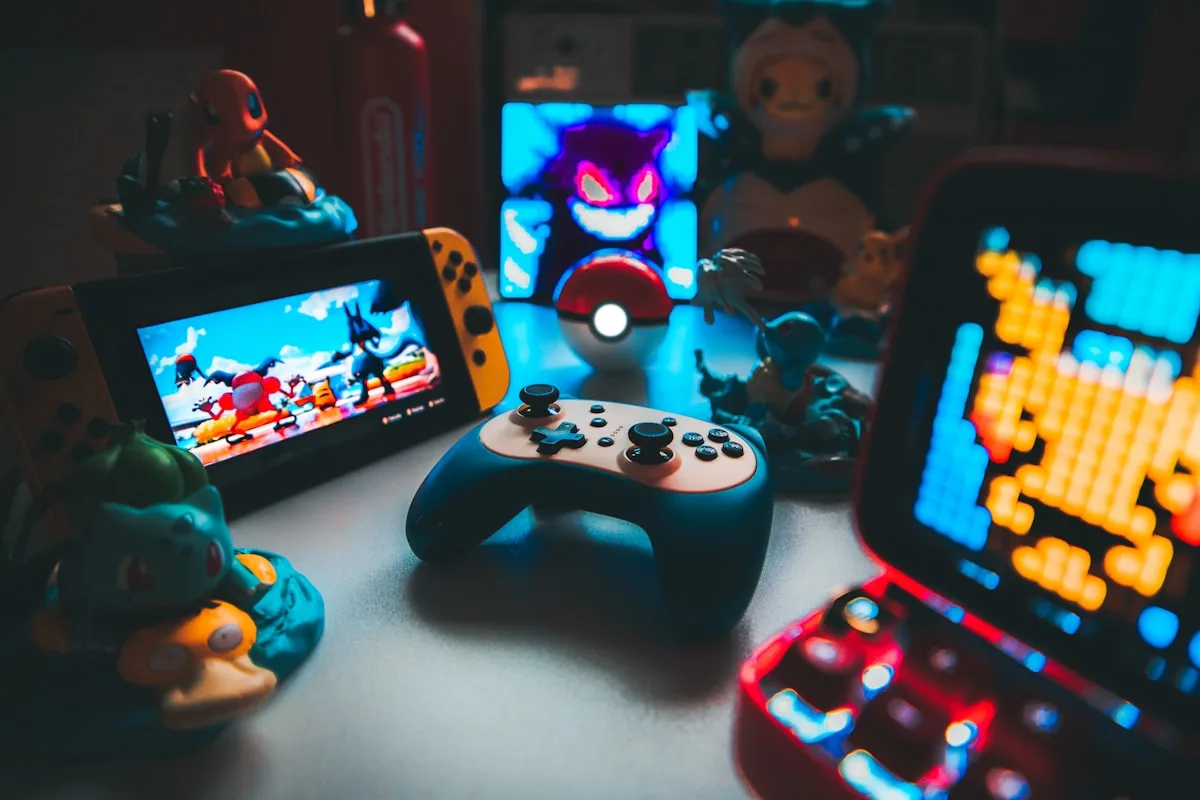 Console portátil e controle sem fio exibindo jogos coloridos em pixel art na tela