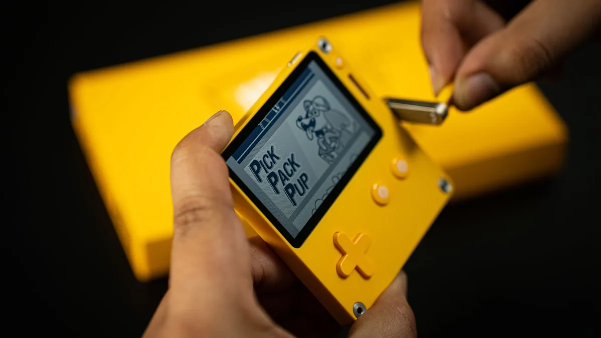 Encaixando cartão de memória em handheld retrô amarelo para carregar biblioteca de jogos