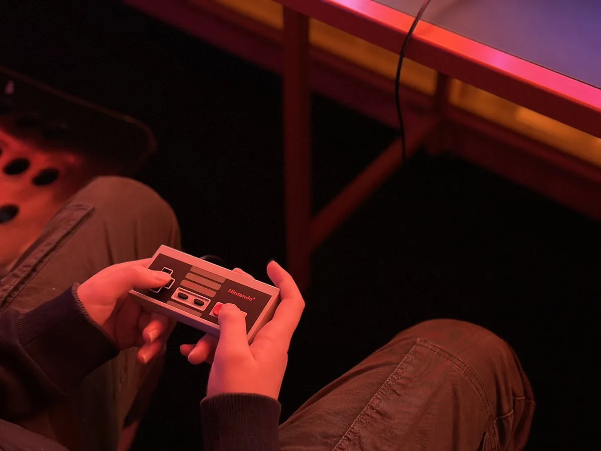 Controle clássico de Nintendo segurado em ambiente com iluminação neon colorida