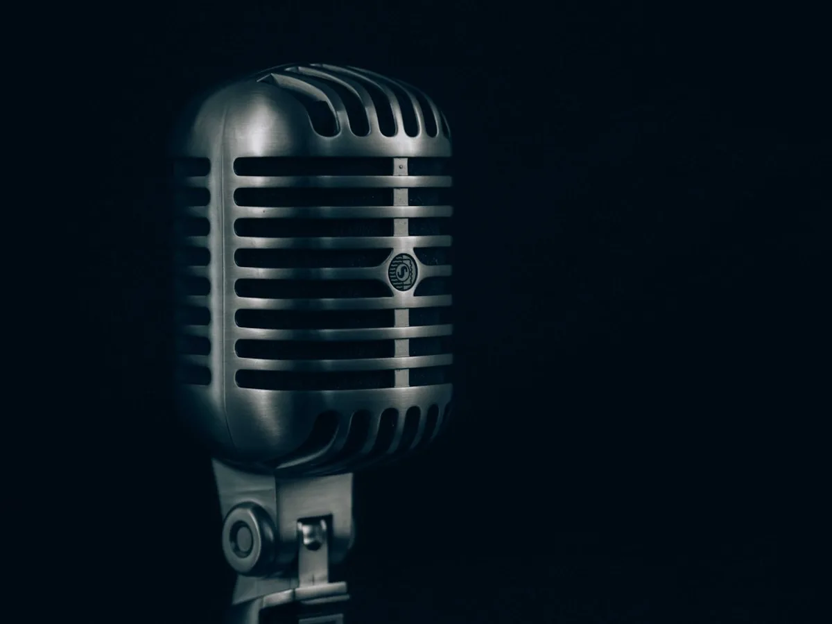 Blue Yeti microfone condensador USB em uso próximo ao rosto com controle de ganho físico visível