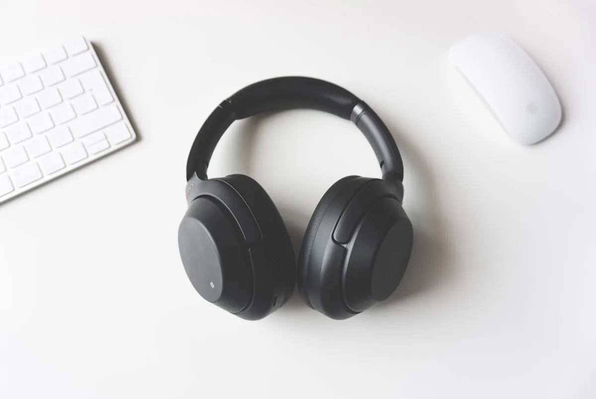 Fone preto sem fio sobre mesa com acessórios de computador para comparar Bluetooth e 2.4 GHz