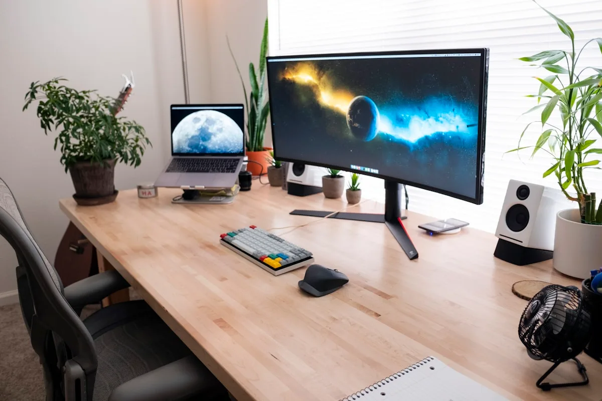 Setup com monitor ultrawide curvo sobre mesa de madeira Setup de mesa de madeira com monitor ultrawide curvo, notebook e teclado mecânico compacto