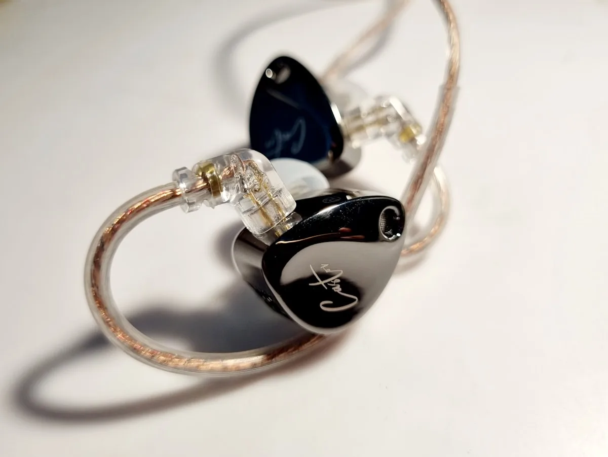 Par de monitores intra-auriculares com ponteiras de silicone sobre uma mesa de madeira
