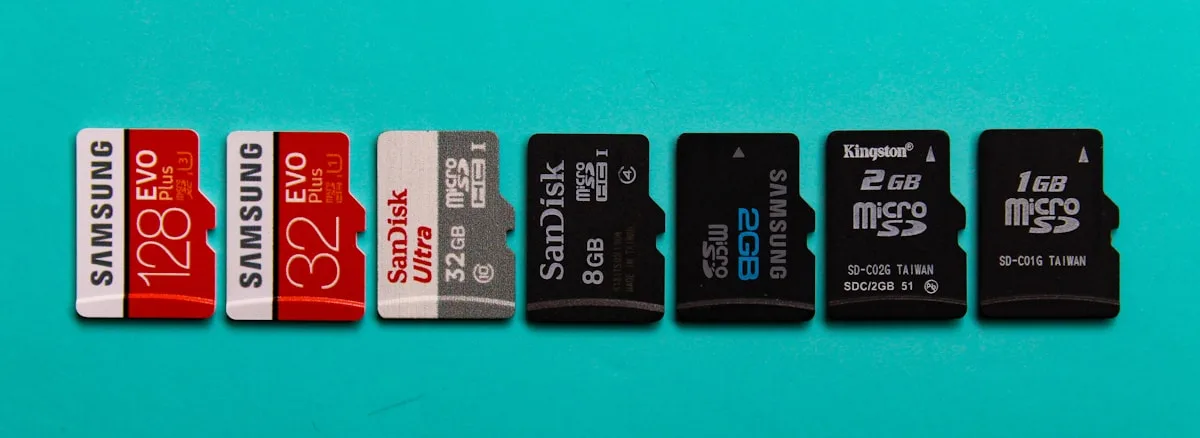 Cartões microSD de diferentes capacidades enfileirados lado a lado sobre fundo azul-turquesa