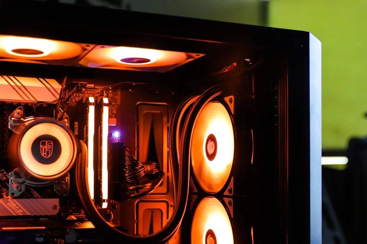 Radiador de water cooler com ventoinhas em tom alaranjado iluminadas, ao lado de módulos de memória RAM dentro do gabinete