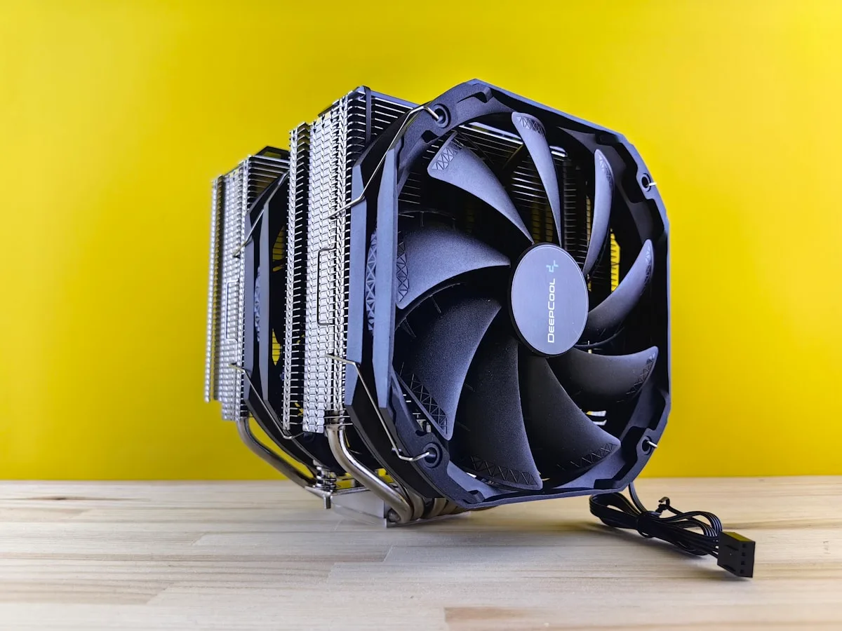 Detalhe do cooler dual-tower Deepcool mostrando heat pipes de níquel e ventoinha frontal com logotipo da marca