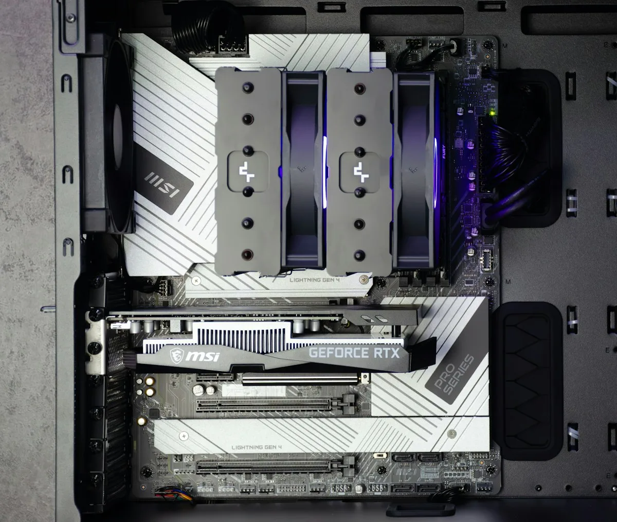 Interior de gabinete gamer com cooler de CPU dual-tower instalado ao lado de placa de vídeo e módulos de memória RGB
