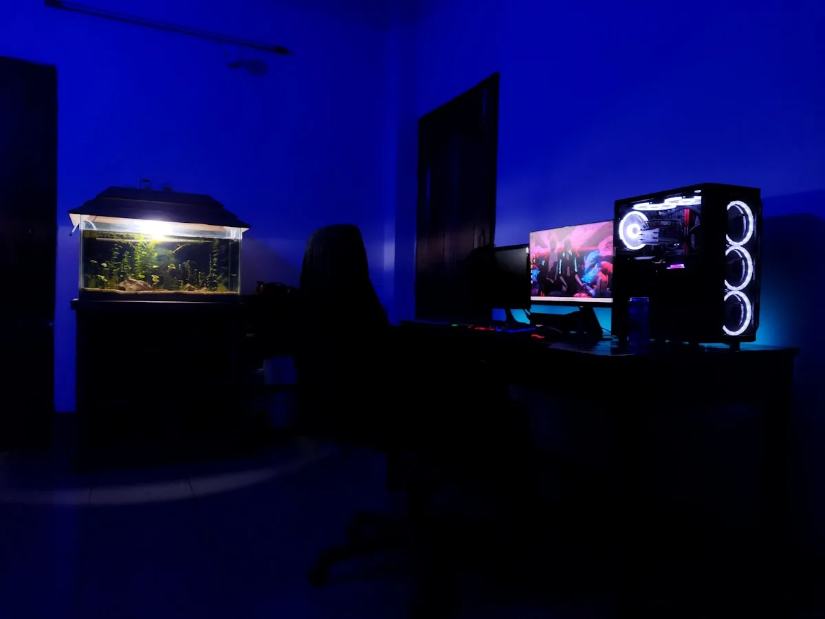 Quarto gamer escuro com fita de led azul no teto e gabinete iluminado ao fundo