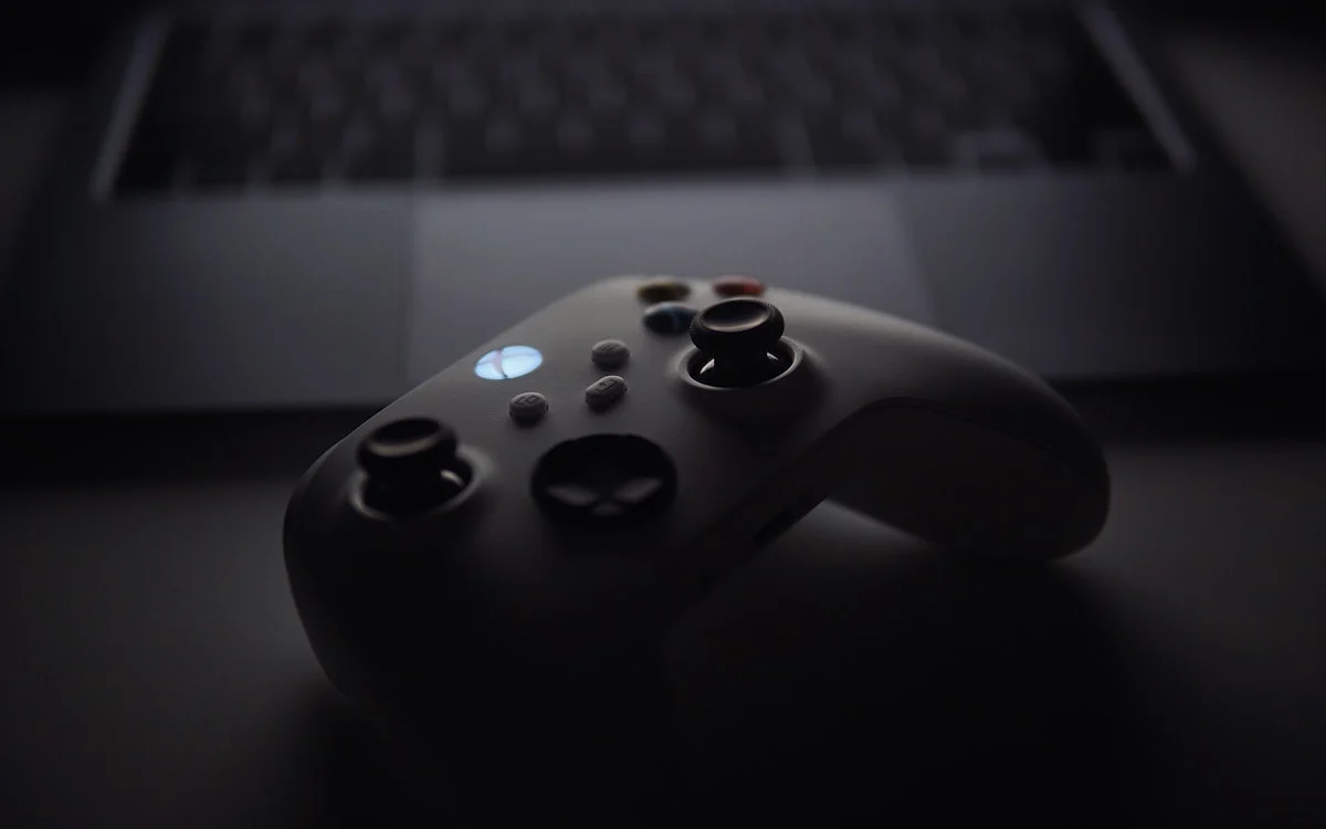Controle Xbox e notebook ao fundo Controle Xbox em primeiro plano com teclado de notebook desfocado ao fundo