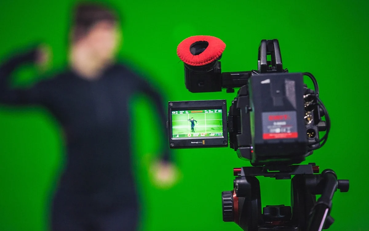 Streamer em frente a fundo verde chroma key com resultado do efeito exibido no monitor ao lado