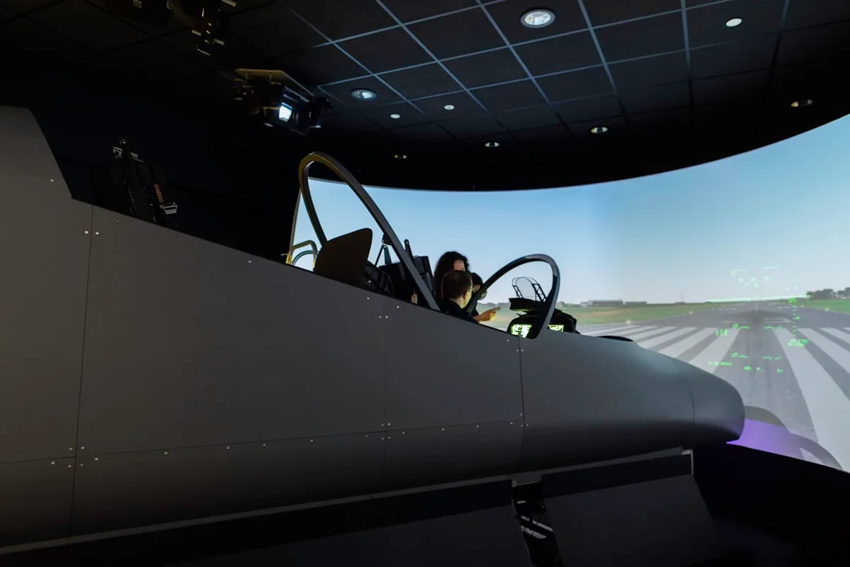 Interior de um simulador de voo profissional com projeção de pista e visor de instrumentos à frente do piloto
