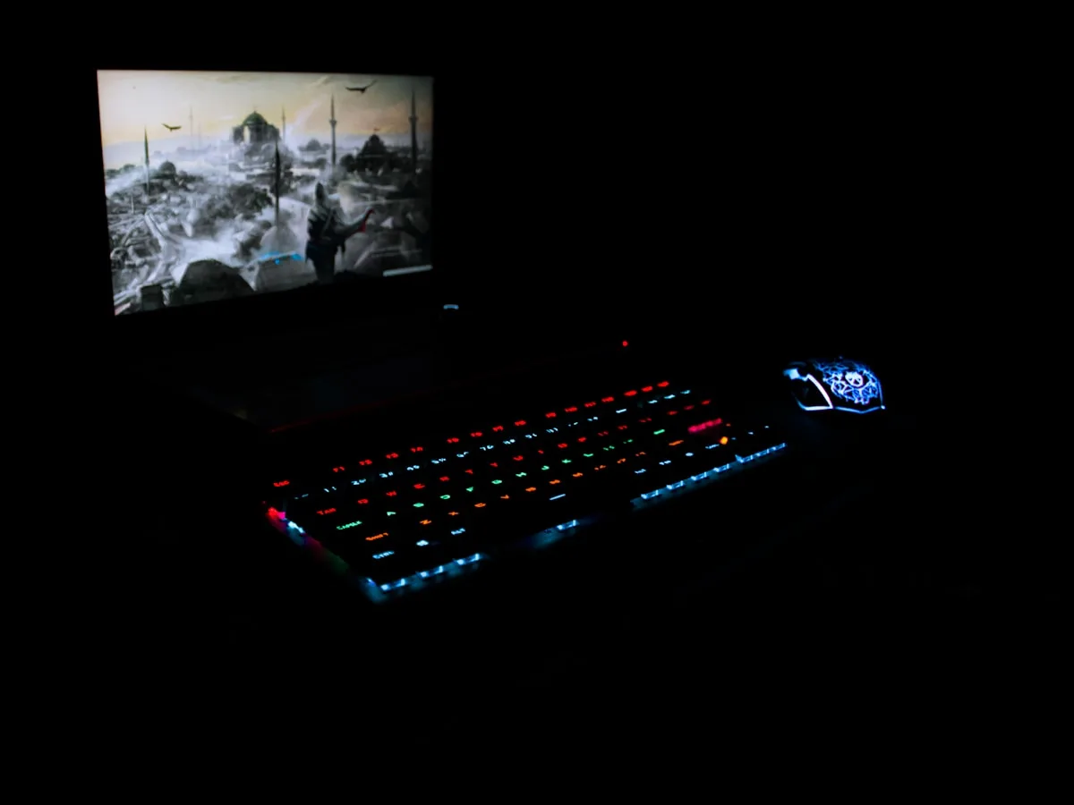 Iluminação e conforto visual no setup gamer Teclado e mouse com RGB aceso enquanto o monitor é a única fonte de luz forte no quarto escuro
