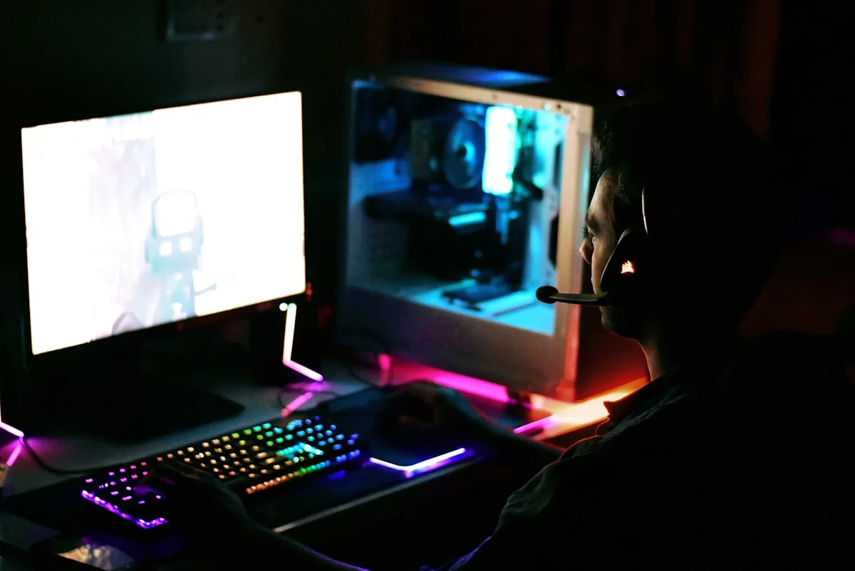Sincronizando luz RGB com jogos e periféricos Gamer de headset jogando com teclado RGB e gabinete iluminado em azul e rosa sincronizados