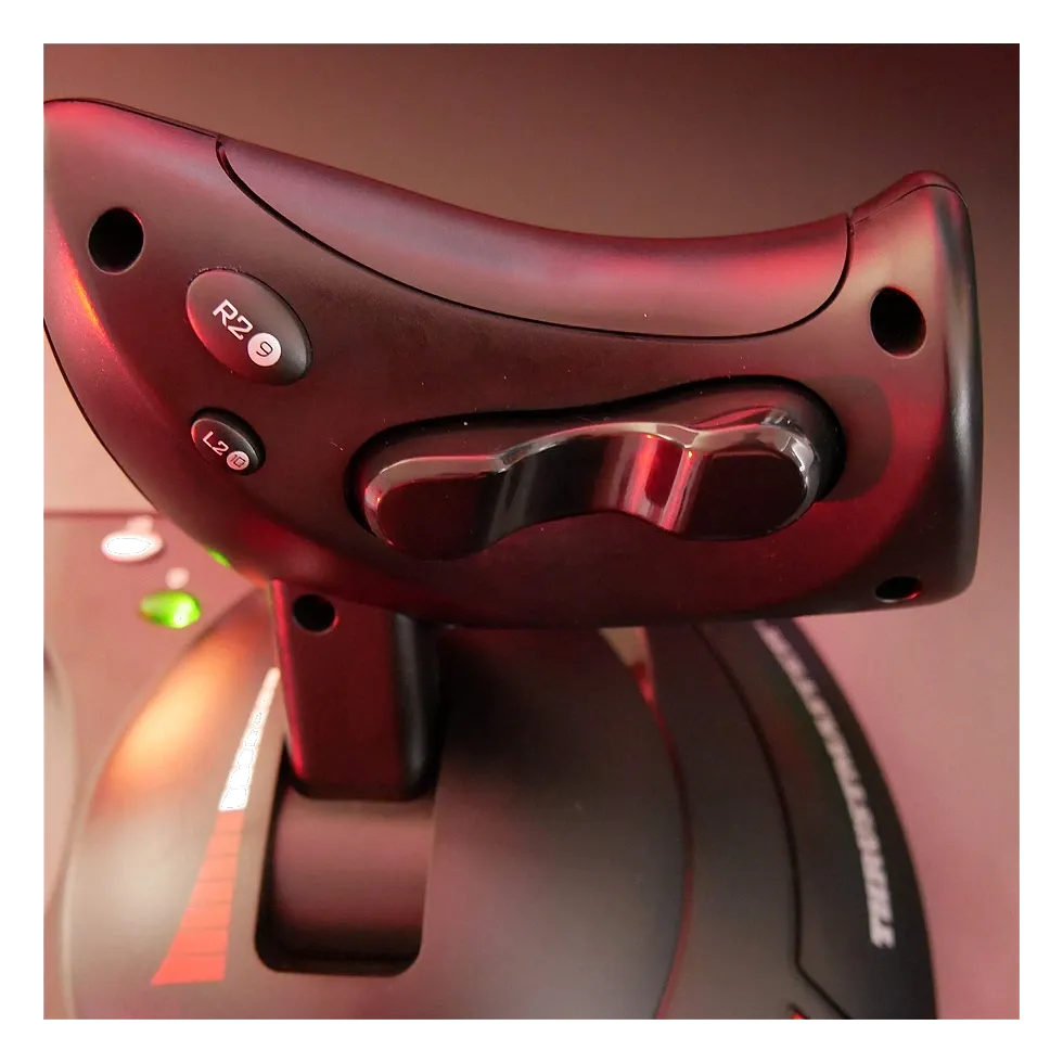 Detalhe do gatilho e dos botões na base do manche Thrustmaster T.Flight Hotas X, iluminado em vermelho