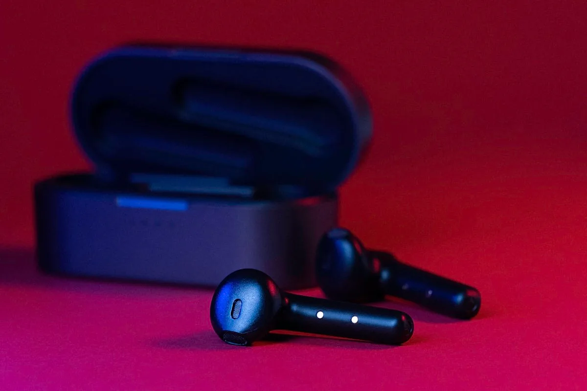 Fones Bluetooth ao lado de celular com jogo aberto em uma mesa de setup gamer