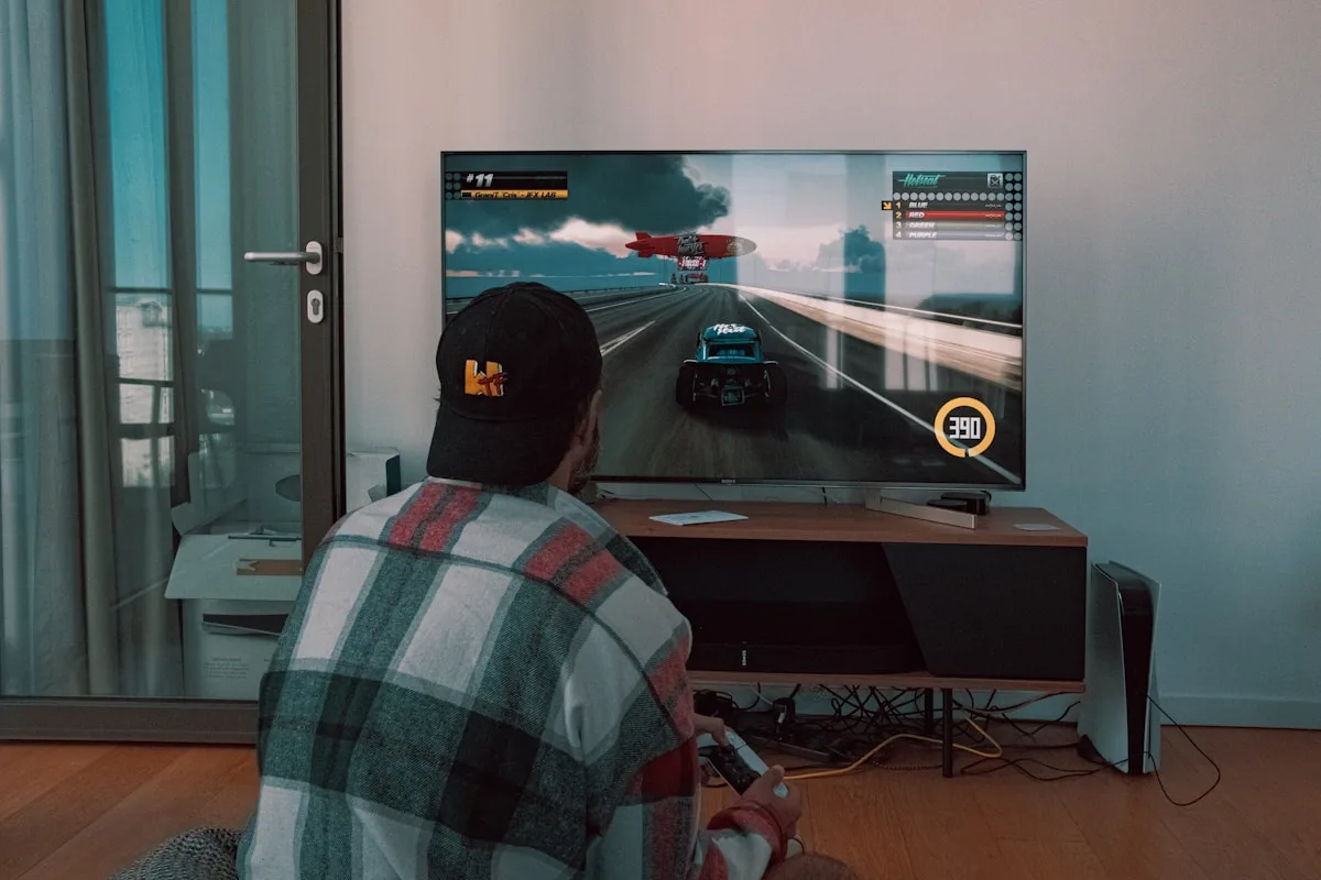 Jogador de costas jogando em TV conectada a console, ambiente de sala com iluminação baixa