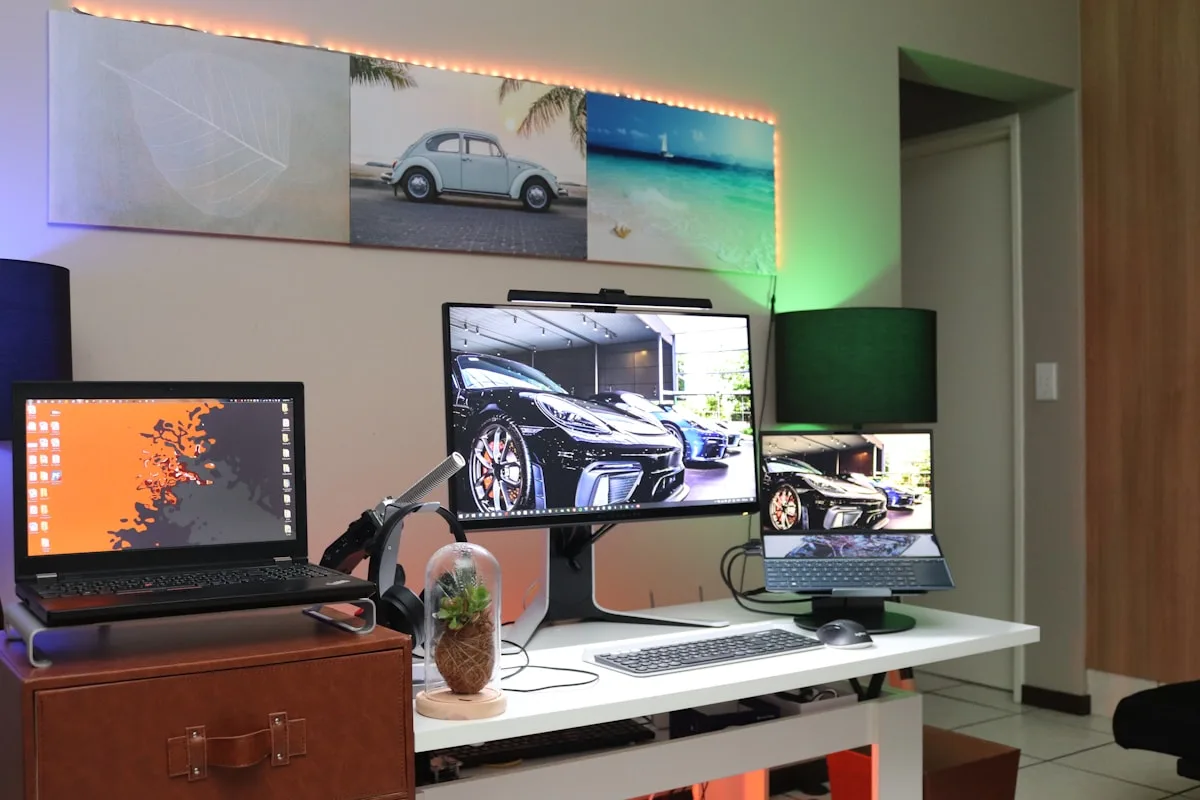 Mesa gamer com monitor externo e notebook conectados lado a lado em setup duplo