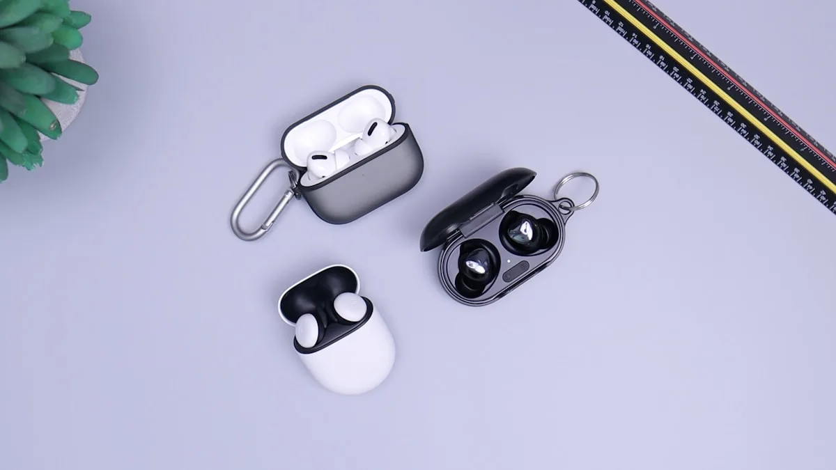 Três pares de fones TWS pretos e brancos alinhados sobre mesa clara em comparação
