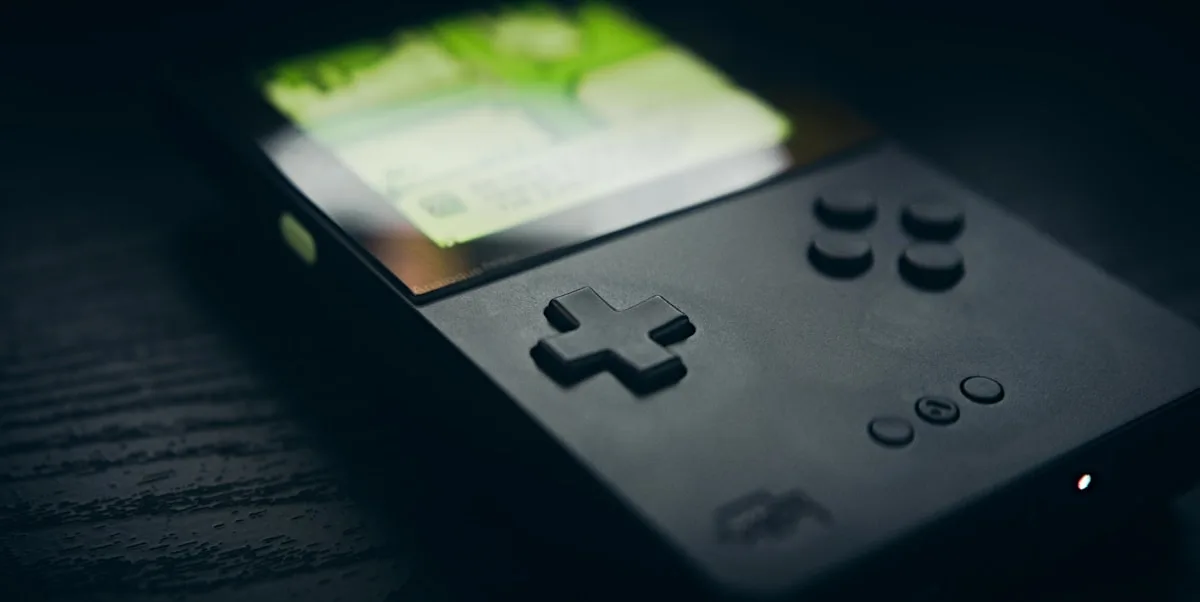 Close de handheld retrô com tela acesa em verde, ideal para emulação portátil de jogos clássicos