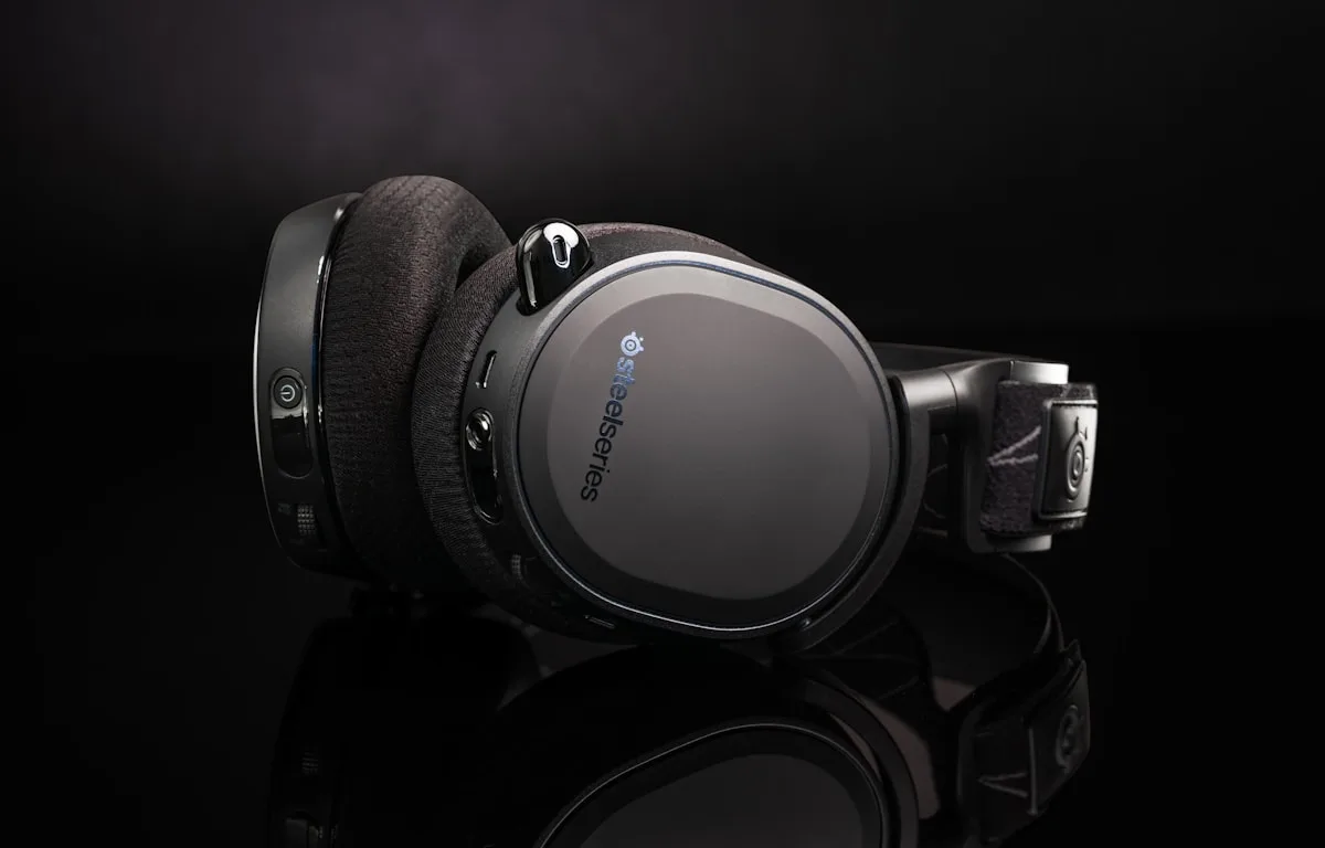 Comparativo de headsets gamer até R$ 1.000 Cinco headsets gamer organizados em mesa de setup gamer com teclado mecânico ao fundo