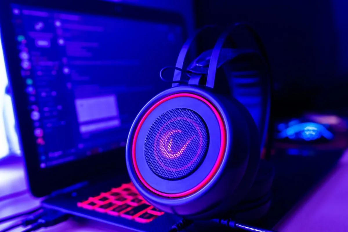 Gamer concentrado usando headset preto em frente a monitor com jogo de tiro em primeira pessoa