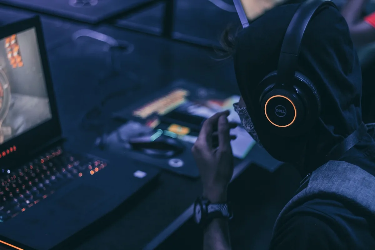 Headset gamer wireless preto apoiado no DualSense ao lado do PlayStation 5 com luz azul
