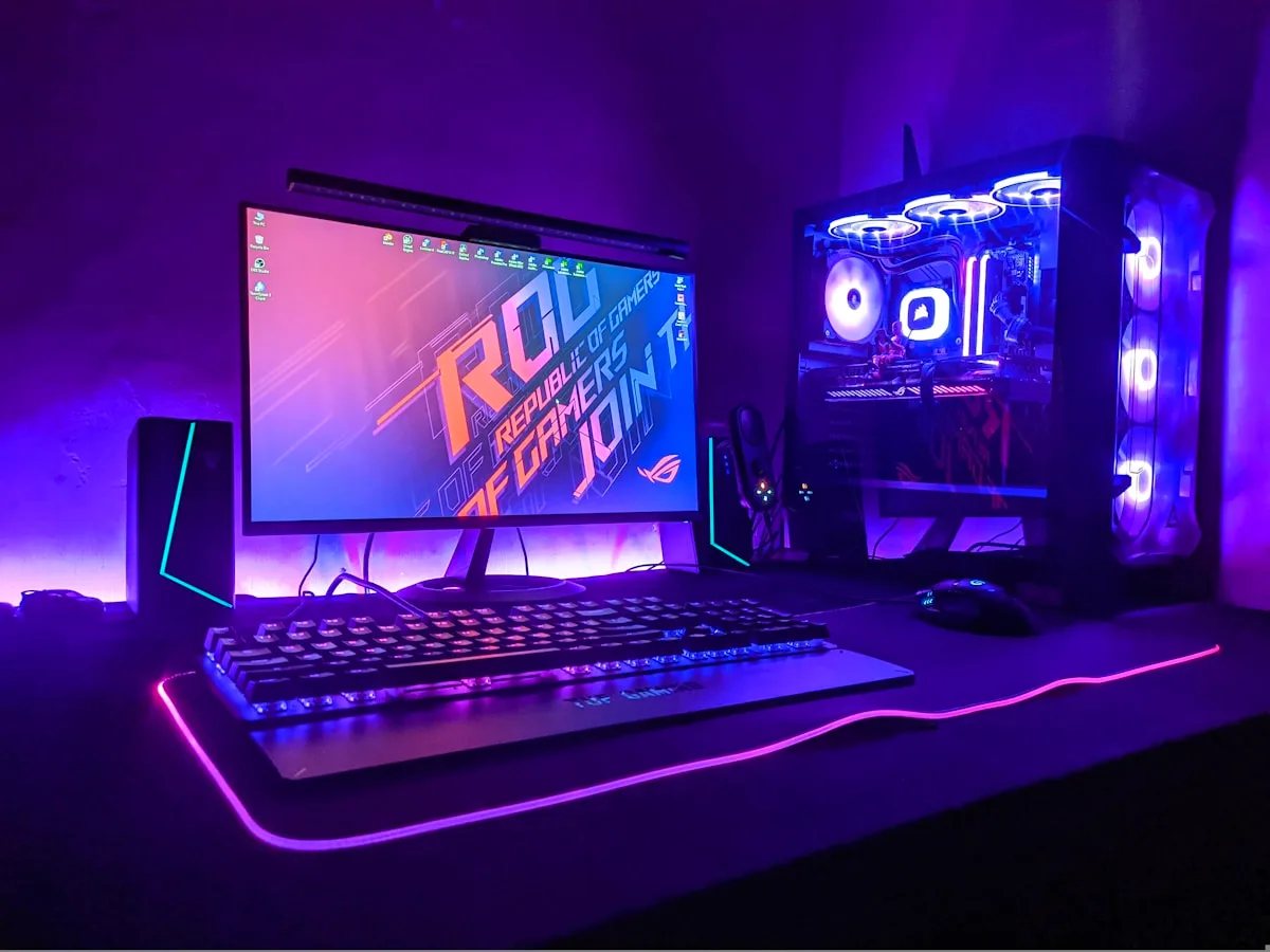 Setup gamer de PC com monitor, teclado e mouse iluminados em roxo sobre a mesa