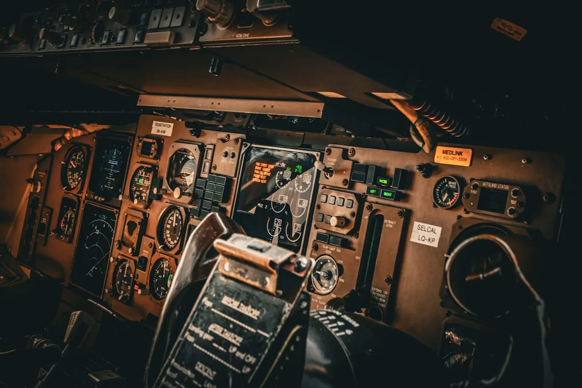 Painel de instrumentos analógico de uma cabine de avião comercial, com mostradores e interruptores iluminados em tom âmbar