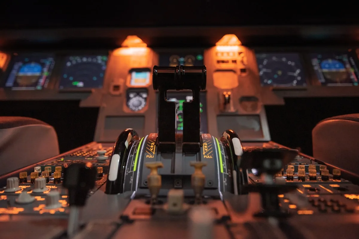 Quadrante de aceleradores de cabine de avião iluminado em tom laranja, com painéis ao fundo