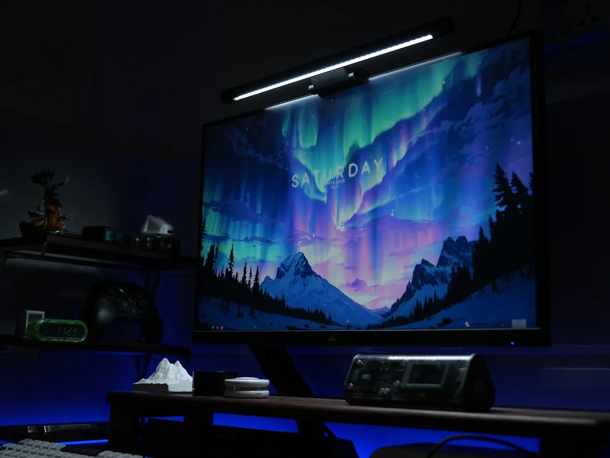 Monitor com barra de luz branca no topo e brilho azul saindo de trás da tela à noite