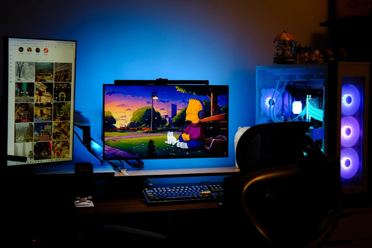 Monitor com barra de luz no topo e luz azul de fundo forte ao lado de gabinete com fans RGB