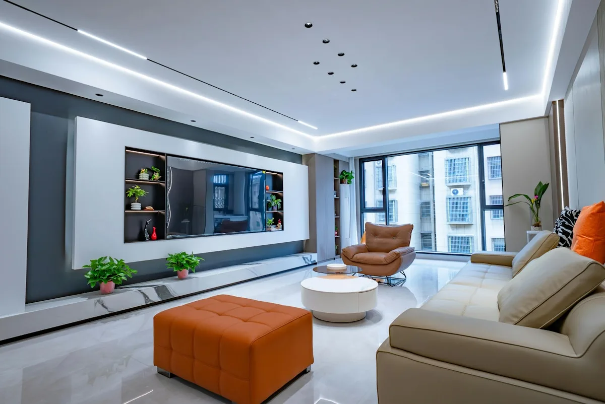 Ambiente com TV e iluminação de LED complementar Sala ampla com TV na parede e fita de LED branca instalada no rasgo do teto ao redor