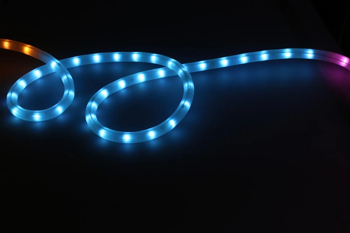 Fita de LED azul e laranja enrolada sobre superfície escura mostrando os pontos de luz individuais
