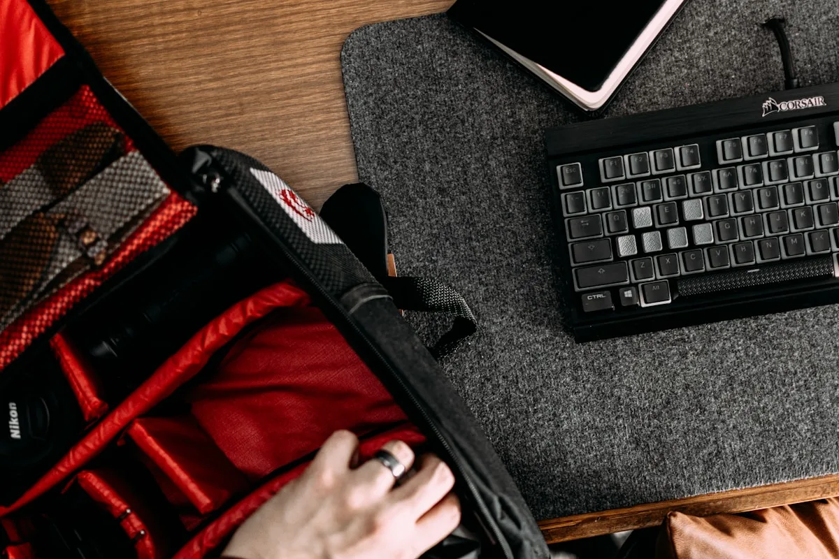 Compartimento interno acolchoado de mochila gamer aberto ao lado de teclado mecânico