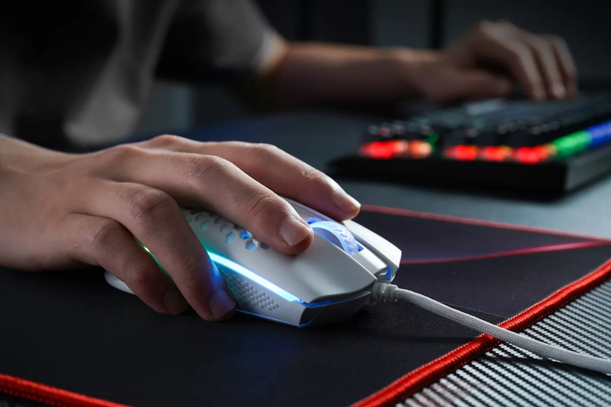Mão segurando mouse gamer de entrada em pegada claw sobre mousepad de setup