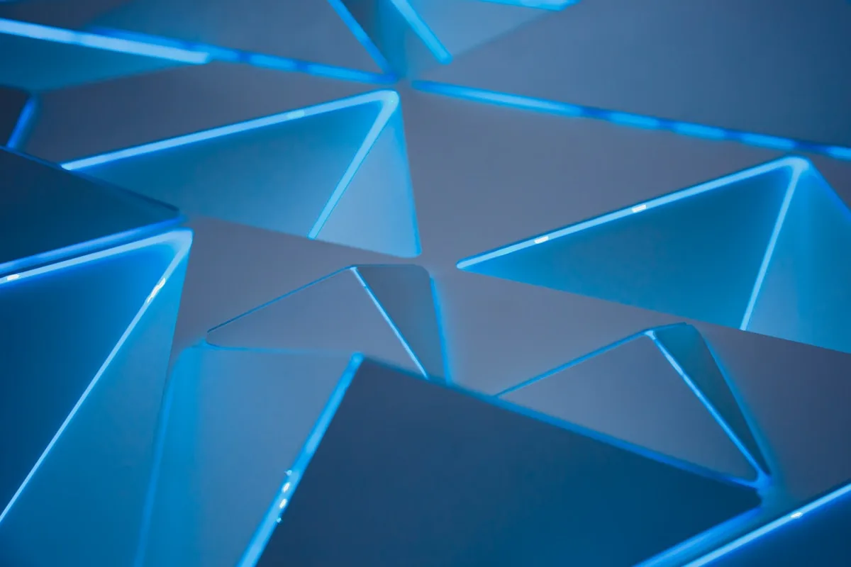 Close de painéis triangulares com bordas iluminadas em azul formando padrão geométrico