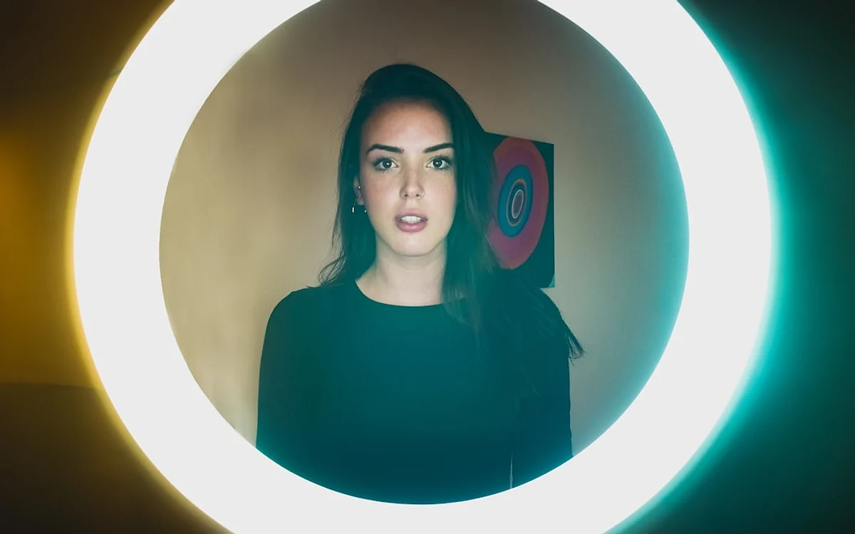Setup de streaming com ring light posicionado atrás do monitor e webcam no centro do aro