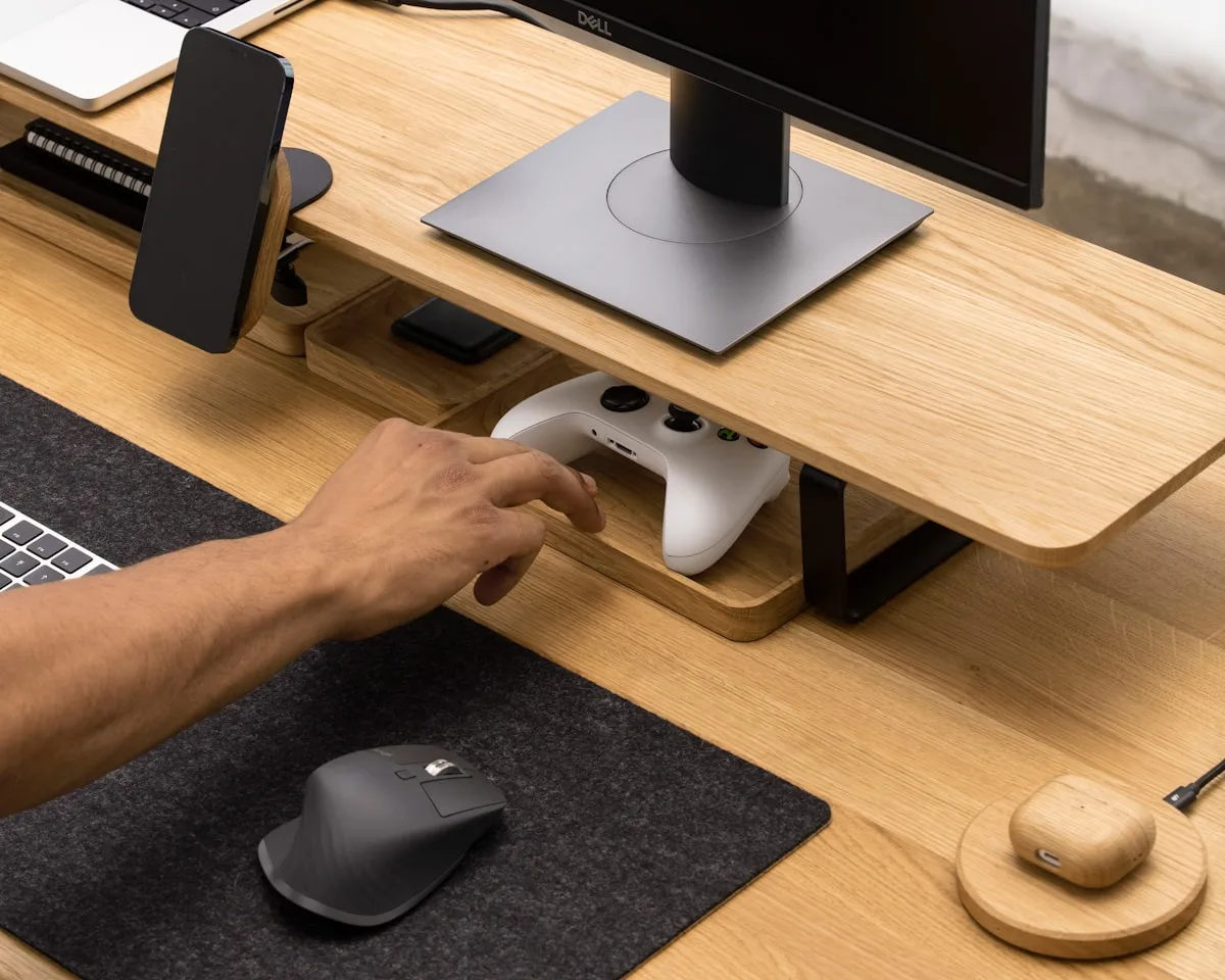 Suporte de monitor em uso num setup organizado Base de suporte de monitor sobre mesa de madeira ao lado de mouse e controle organizados