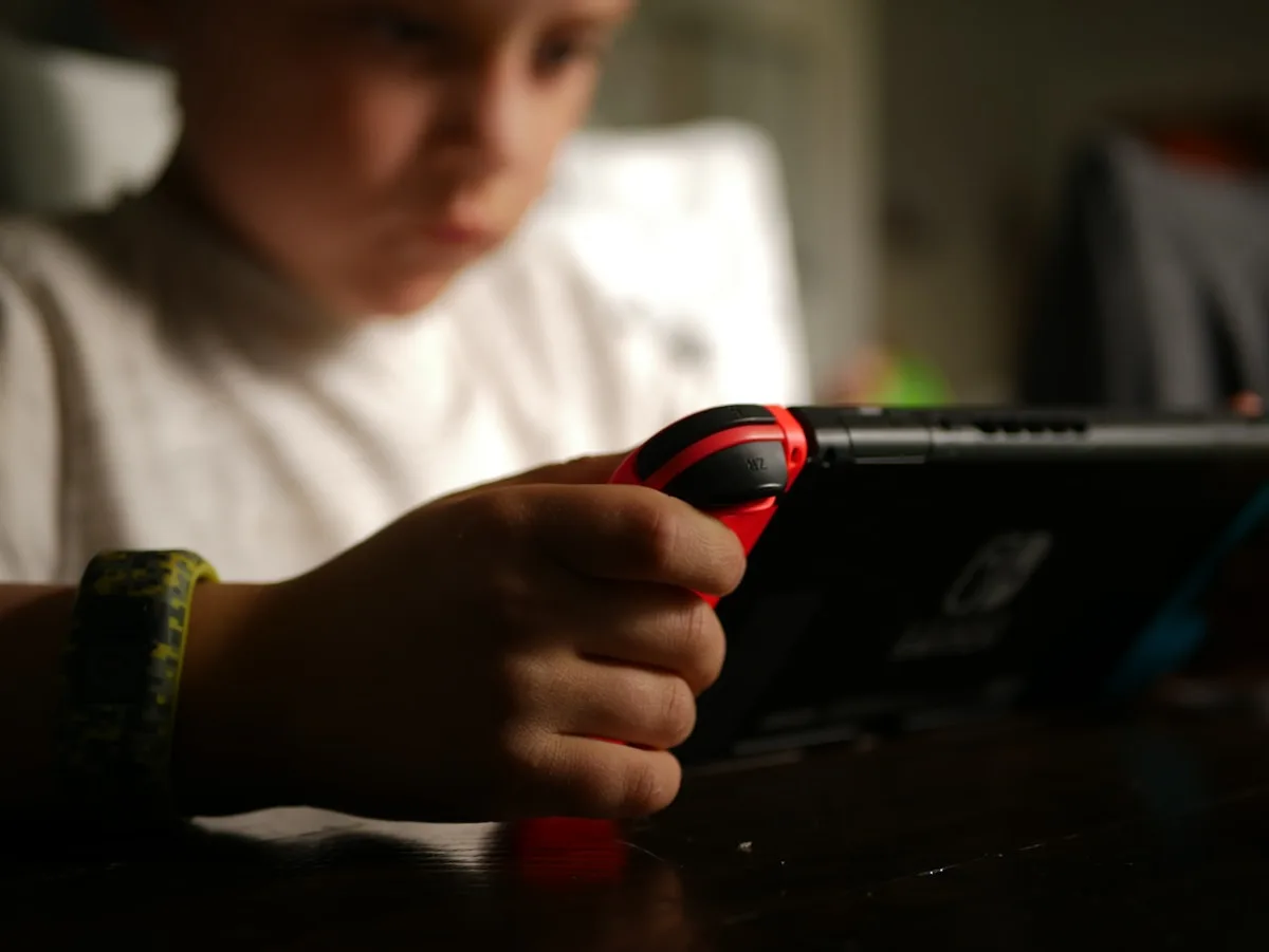 Garoto sentado no sofá jogando videogame portátil