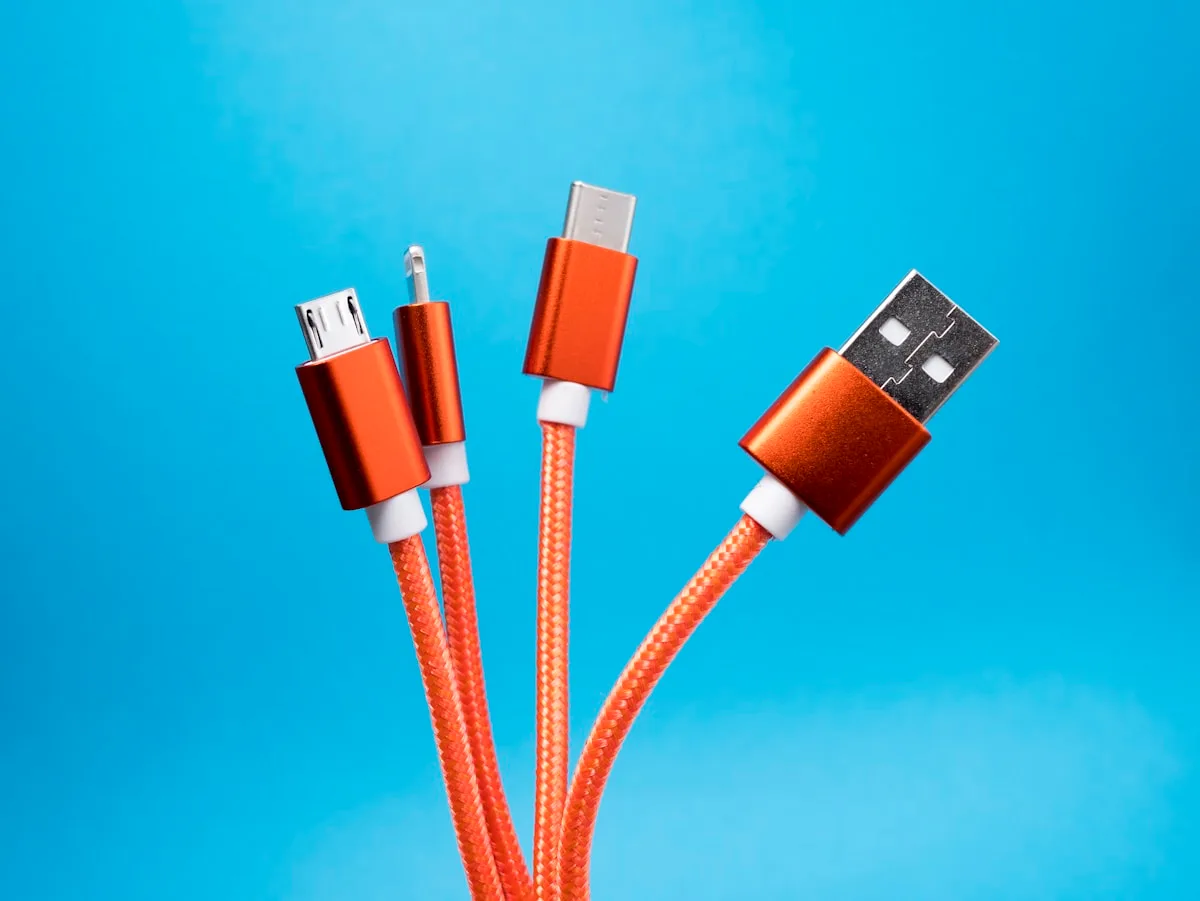Cabos USB-C e micro-USB laranja trançados sobre fundo azul em close-up