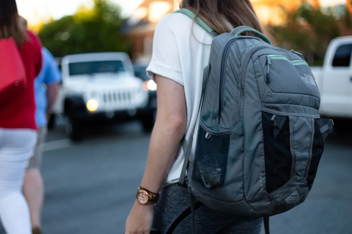 Pessoa carregando mochila cinza nas costas ao ar livre, alças ajustadas para trajeto longo