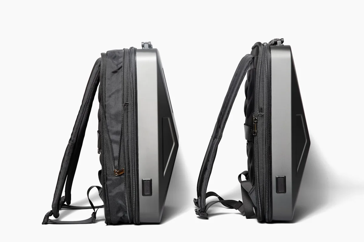 Duas mochilas com casco rígido vistas de perfil mostrando a curvatura da proteção externa e as alças acolchoadas