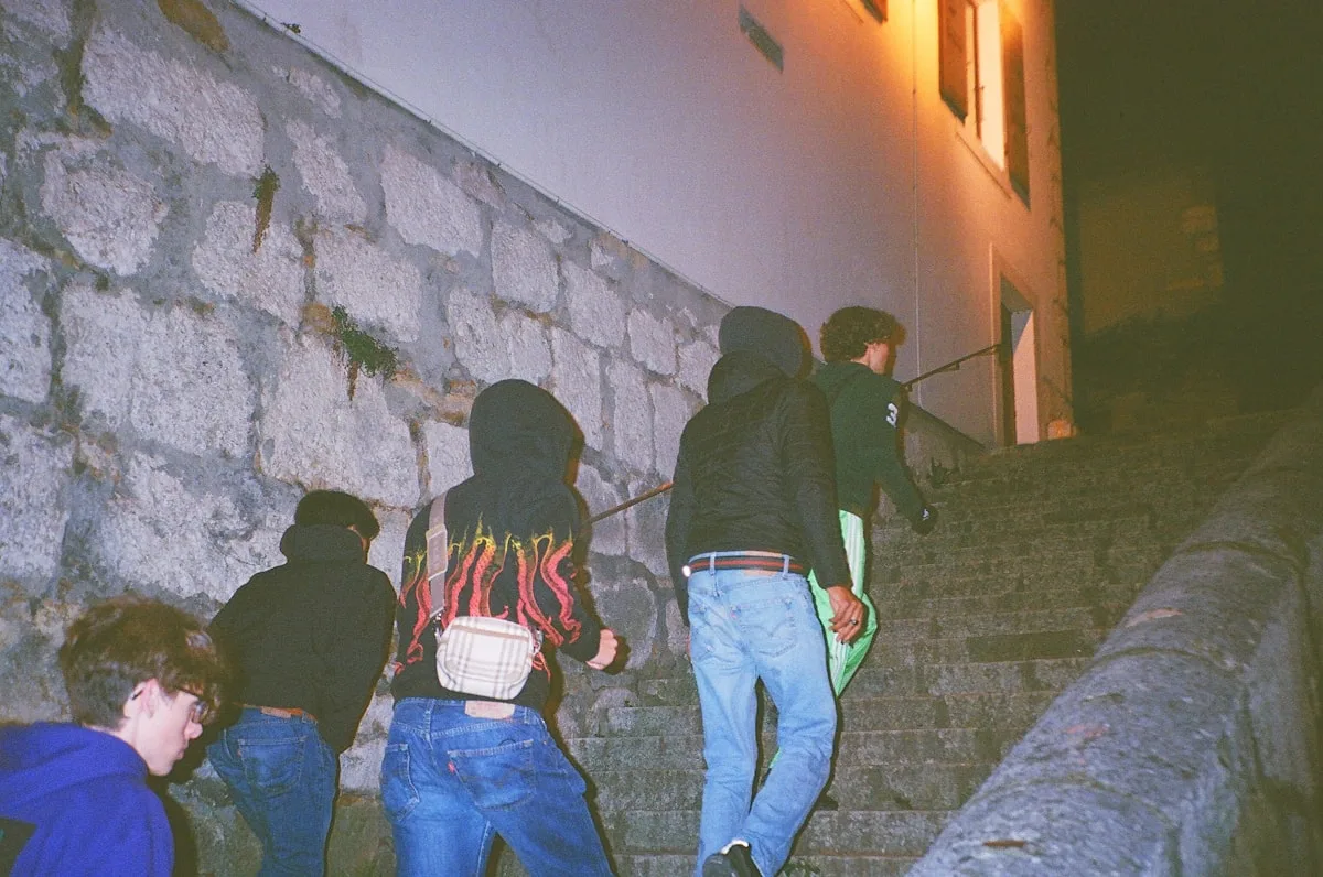 Grupo de amigos caminhando à noite com mochilas nas costas a caminho de um evento