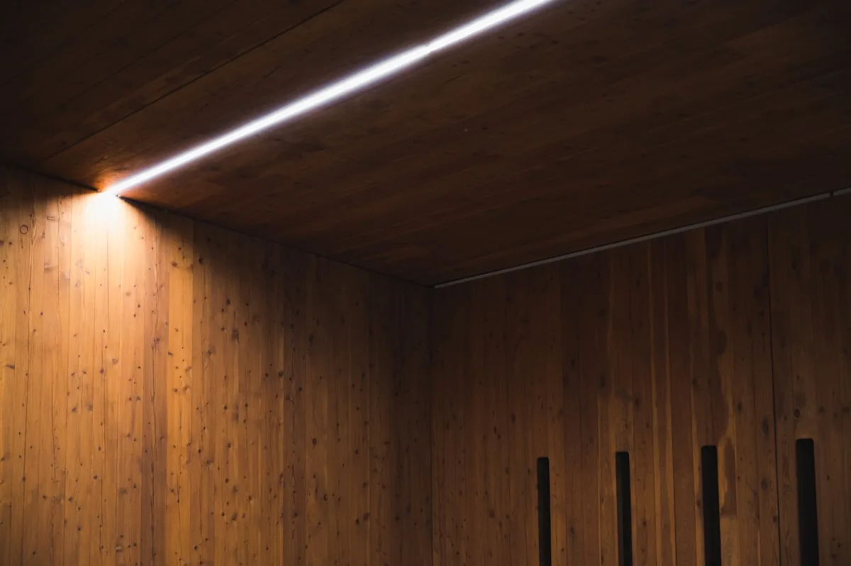 Canto de parede revestido em madeira iluminado por luz branca quente, clima que o Elements reproduz