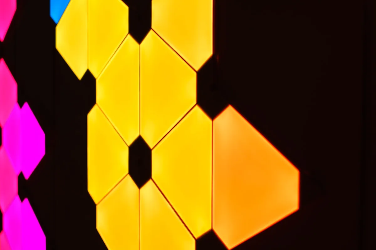 Painéis hexagonais em close-up com luzes amarela, rosa e laranja simultâneas