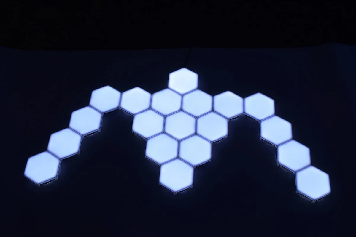 Painéis hexagonais brancos conectados formando desenho assimétrico na parede escura