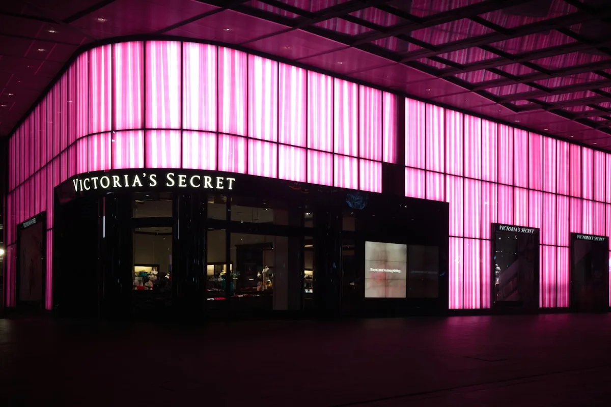 Letreiro de neon LED decorando um ambiente Letreiro neon rosa iluminado entre plantas penduradas e luzes amareladas em ambiente decorado