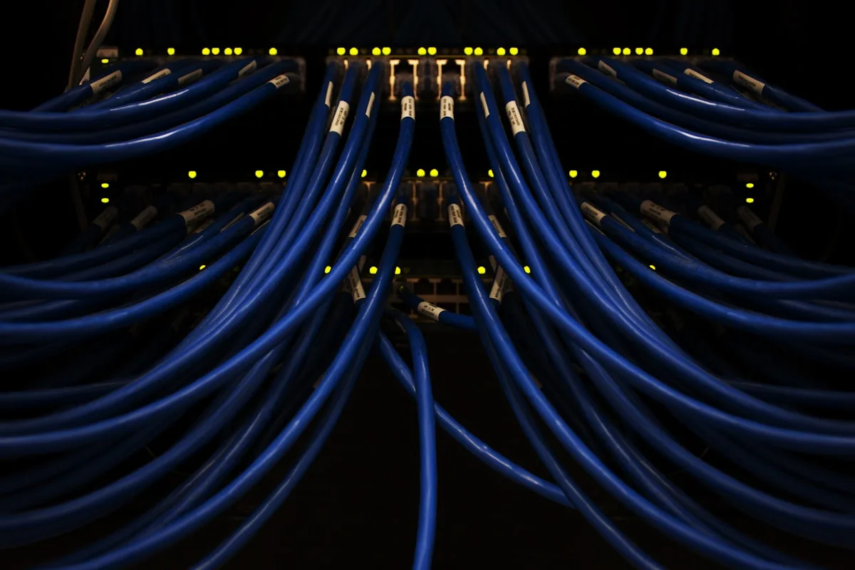 Painel de rack com dezenas de cabos de rede azuis organizados, ambiente típico de KVM sobre IP e rackmount
