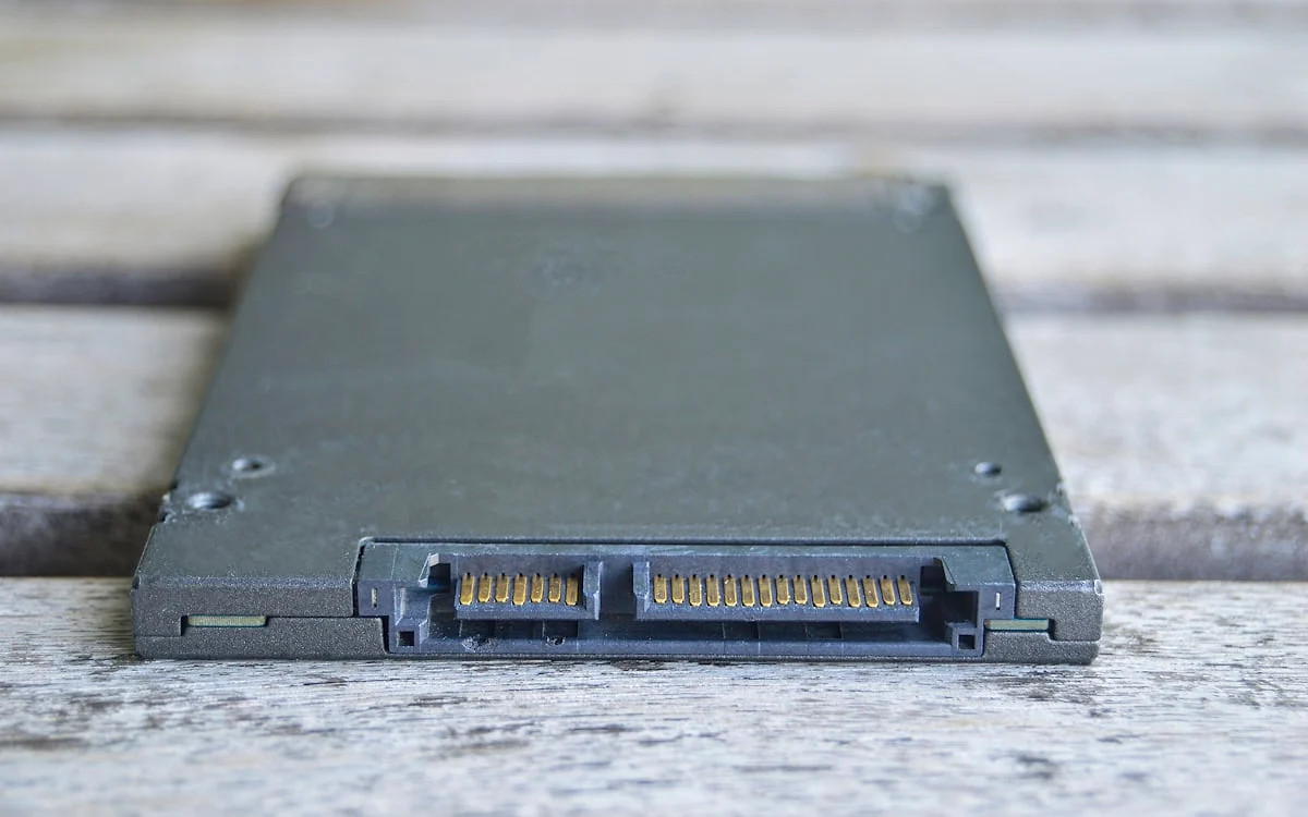 SSD externo portátil conectado por cabo USB-C a um notebook sobre mesa de trabalho