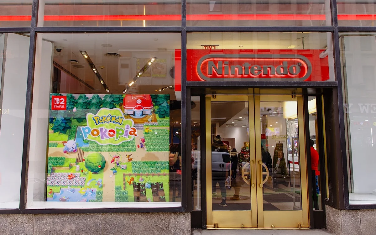 Loja de games na época de um grande lançamento Fachada de loja de games com vitrine iluminada exibindo pôster de um lançamento recente